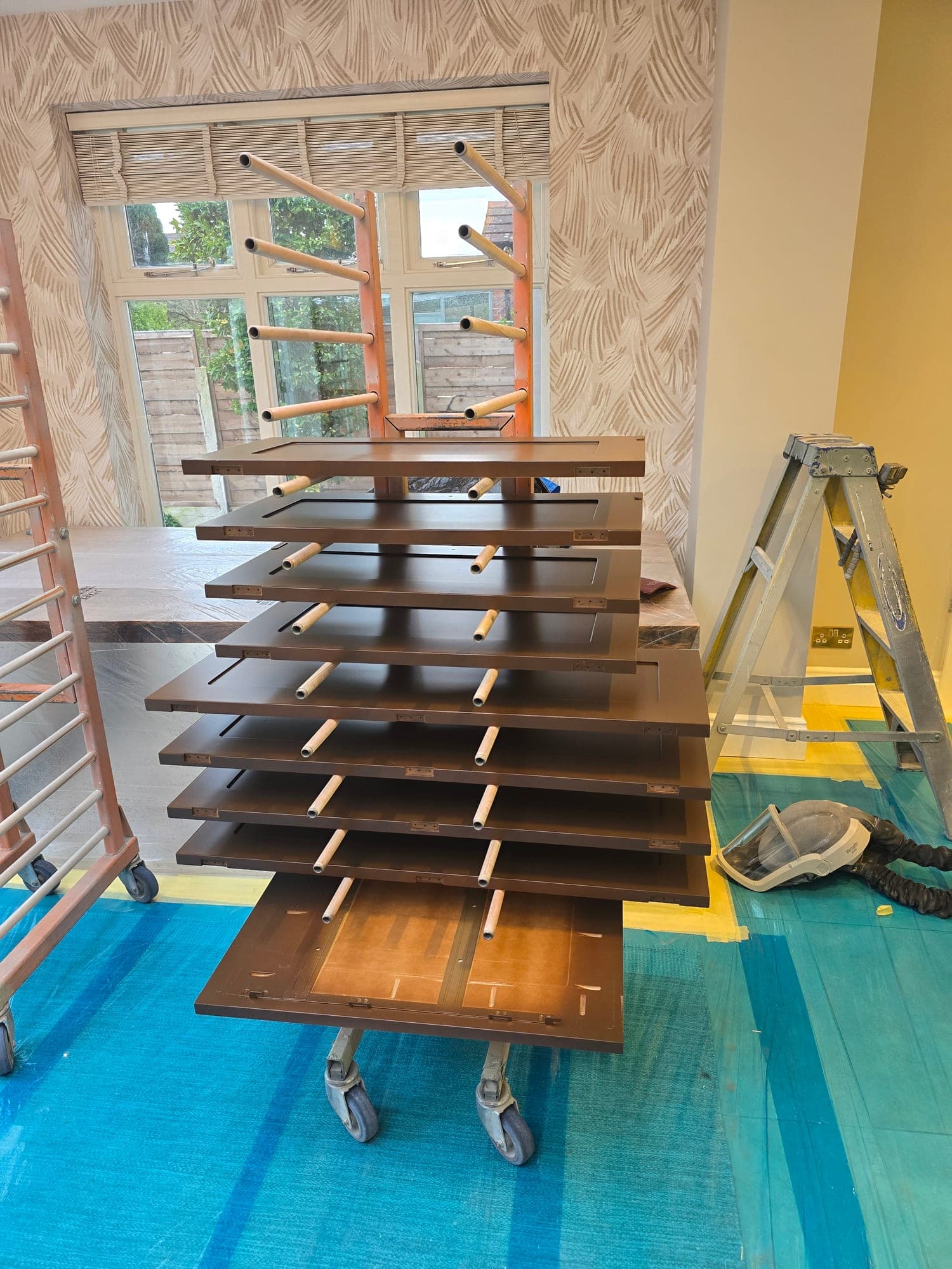 Kitchen doors off and on the drying rack after being hand-sprayed on site