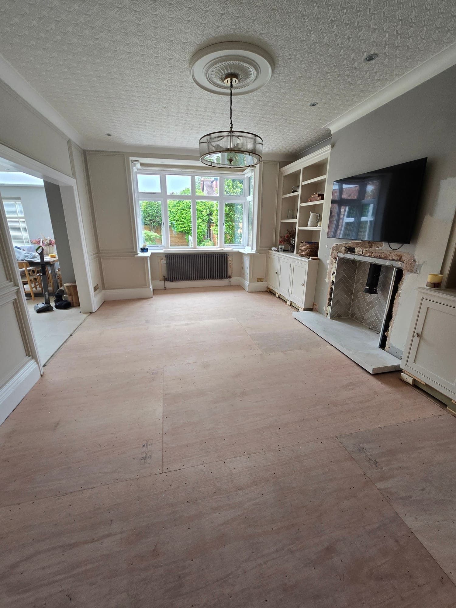 The living room part way through, with the alcove shelving built and the fireplace opening tiled, the floor still on plywood