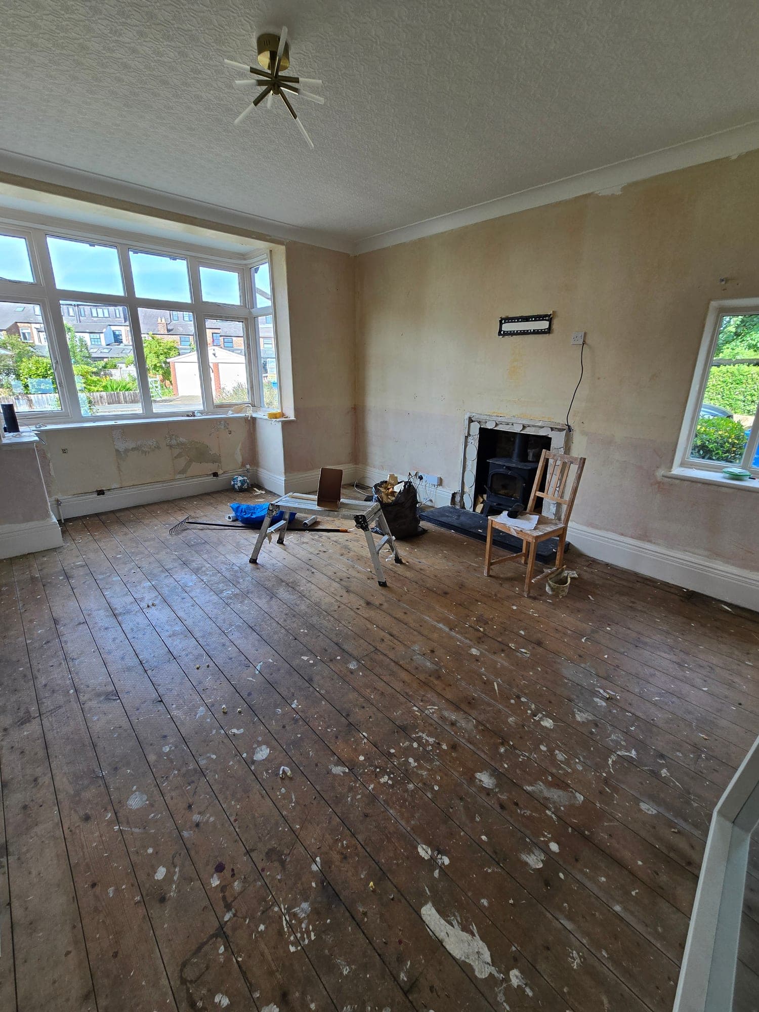 The formal lounge taken back to bare floorboards with the original fireplace opened up