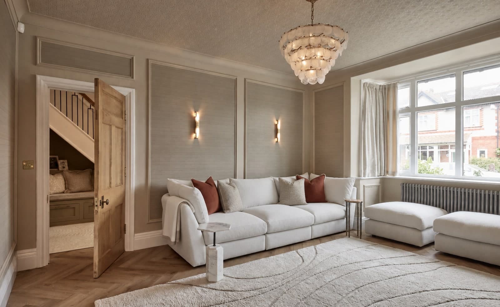 The finished sofa wall in the formal lounge, with panelling, grasscloth and a chandelier
