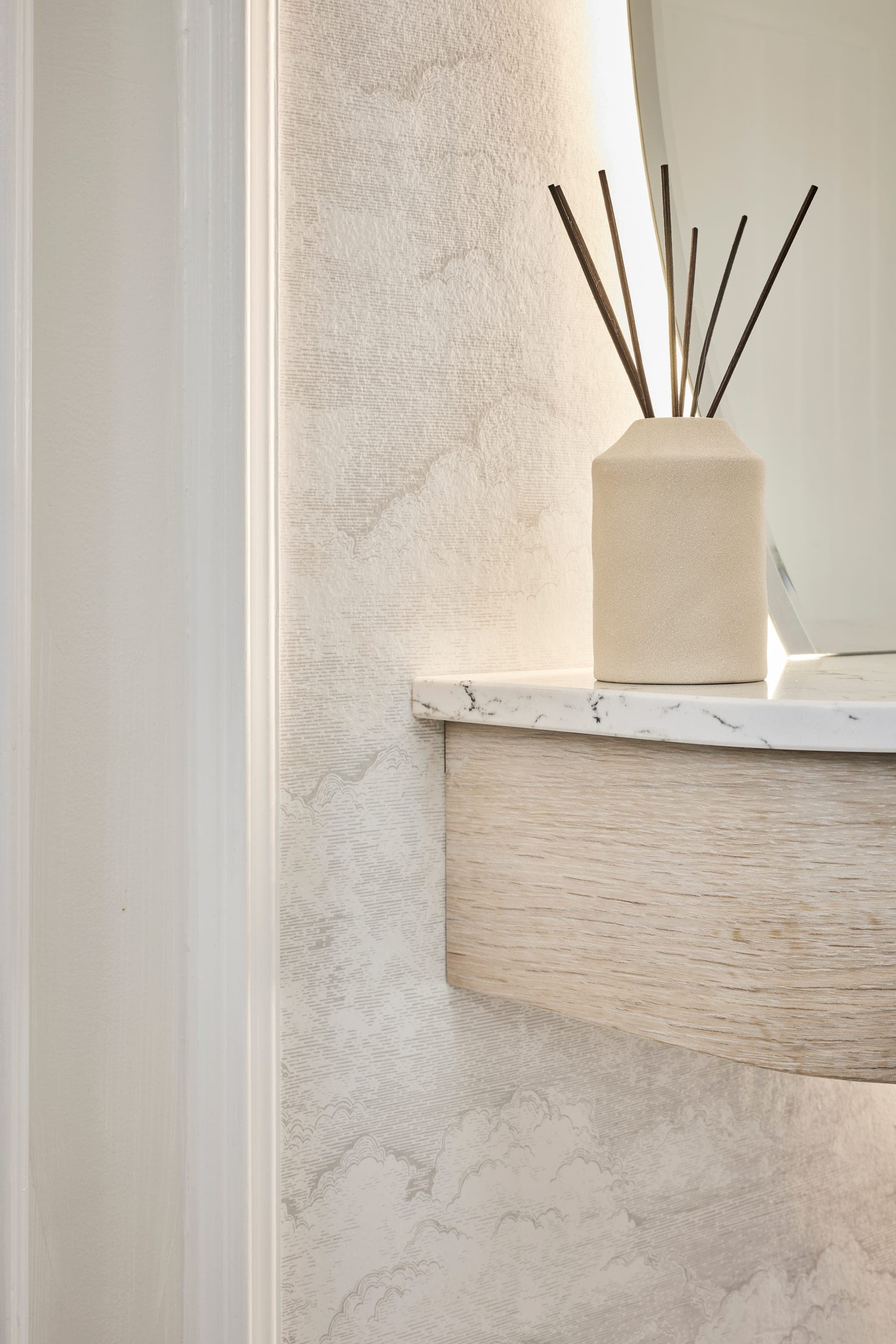 The backlit mirror and textured plaster wall, with a styled console