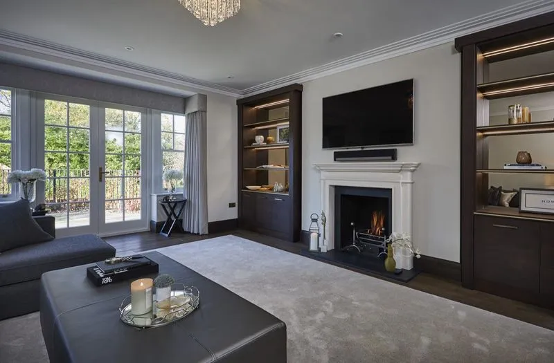 An elegant living room with a fireplace and bespoke shelving in a Hale Barns home