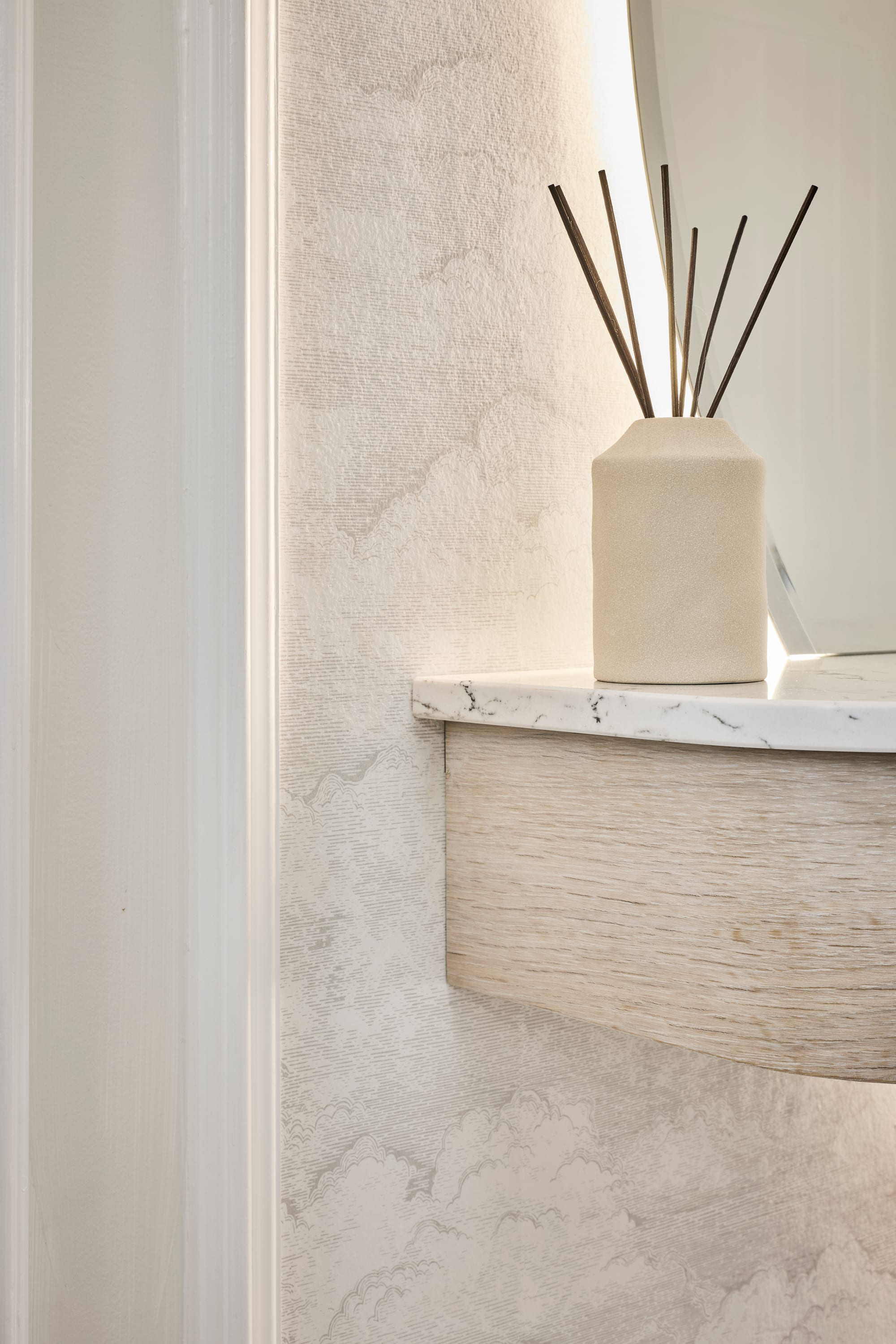 The backlit mirror and textured plaster wall, with a styled console